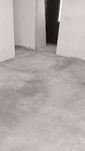 Worker using a steel trowel to smooth and finish the cement screed surface for a polished look.